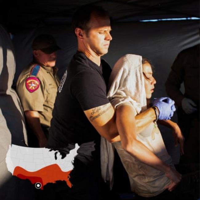 A firefighter lifts a migrant woman suffering from heat exhaustion o<em></em>nto a stretcher